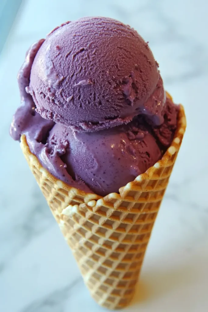 Plum ice cream in cone with basil