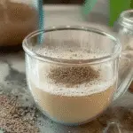 Glass mug filled with bariatric seed trick drink made of chia, fennel, and flax seeds on a kitchen counter.