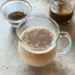 Creamy bariatric seed trick recipe served in a clear glass mug with chia seeds floating on top, on a light marble countertop.