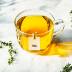 Steaming mug of FGO organic green tea on white marble