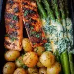Grilled salmon served with roasted baby potatoes and asparagus on a plate.