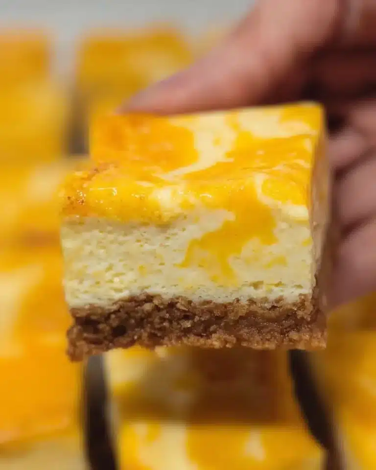 Delicious mango cheesecake bars garnished with fresh mango slices.