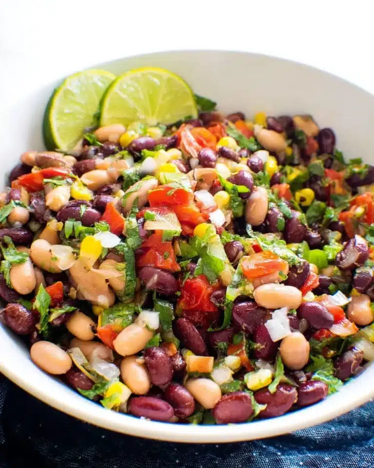 Colorful Mexican bean salad with beans, vegetables, and dressing.