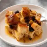 A serving of traditional Irish bread pudding with raisins and custard sauce