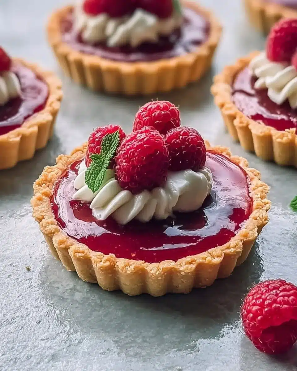 Vegan raspberry curd tarts garnished with fresh raspberries and mint