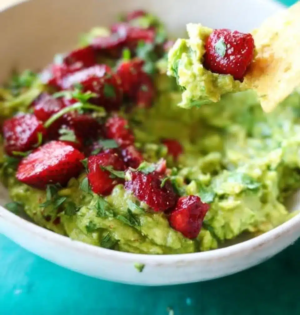 Bowl of roasted strawberry guacamole with fresh strawberries and cilantro