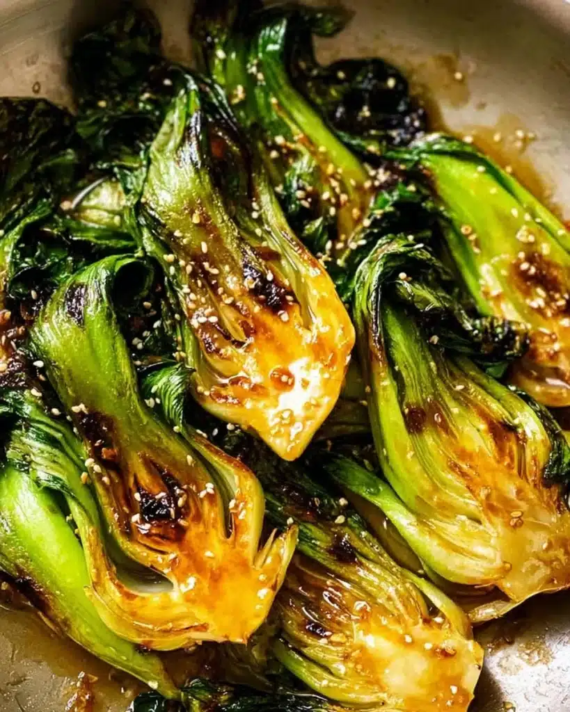 Sautéed baby bok choy in a pan, garnished and ready to serve.