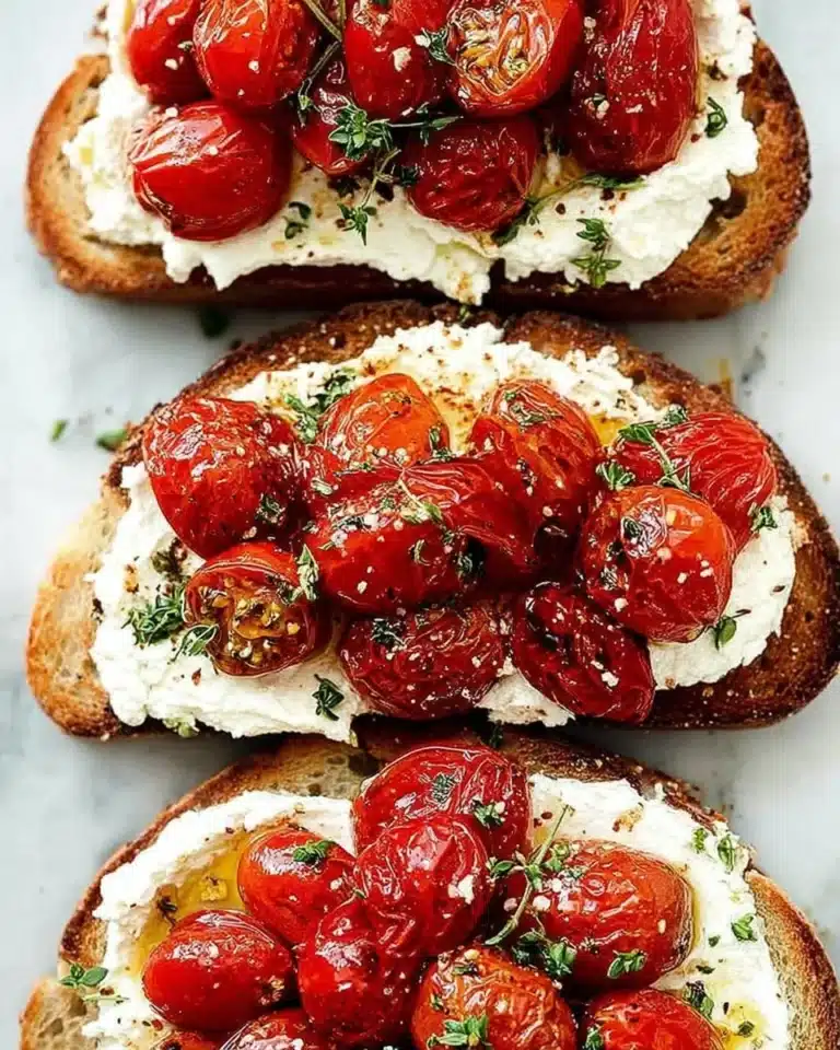 Whipped ricotta toast crostini with roasted tomatoes garnished on a platter