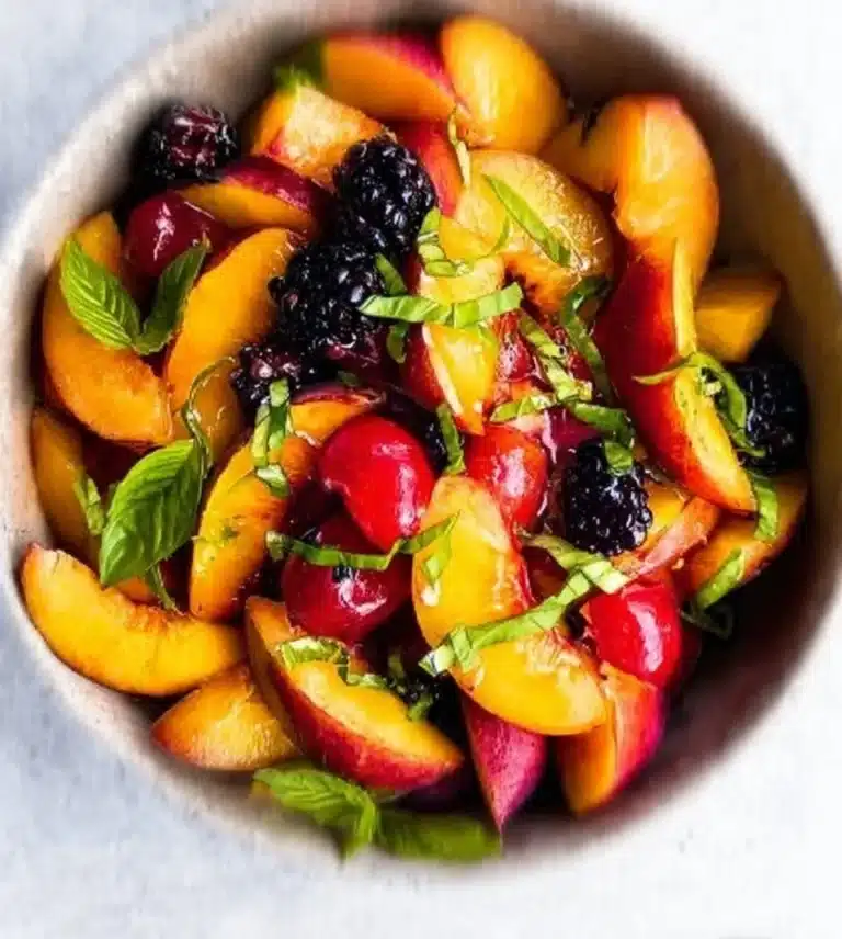 Bowl of Honey Lime Basil Peach Fruit Salad with vibrant peaches and fresh basil