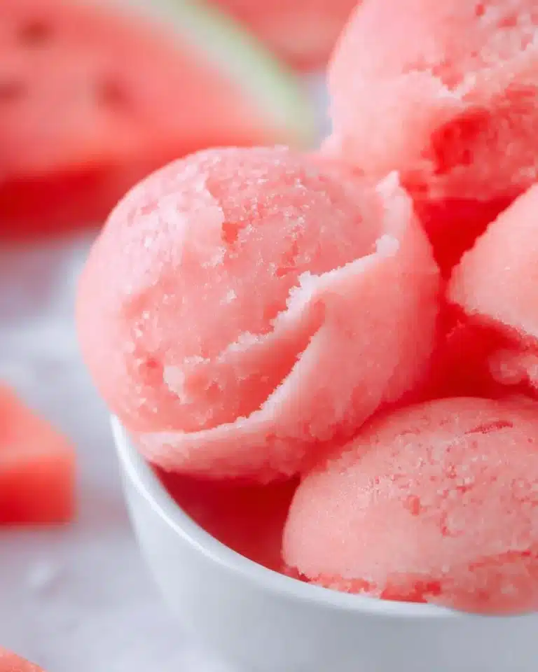 A vibrant bowl of homemade watermelon sorbet topped with mint leaves