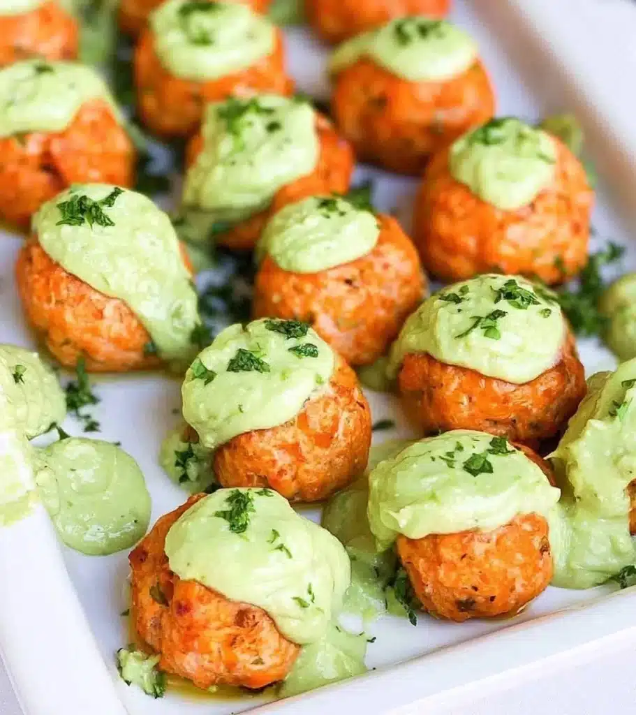 Plate of homemade salmon meatballs garnished with herbs and served with sauce