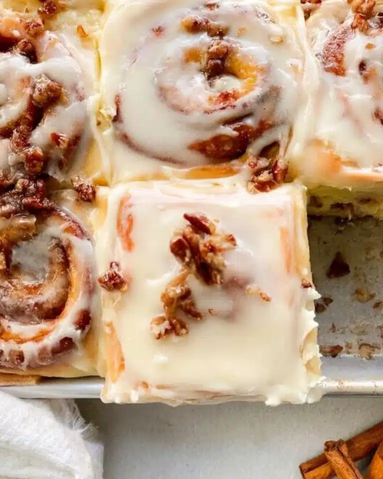 Freshly baked apple pecan cinnamon rolls topped with icing.