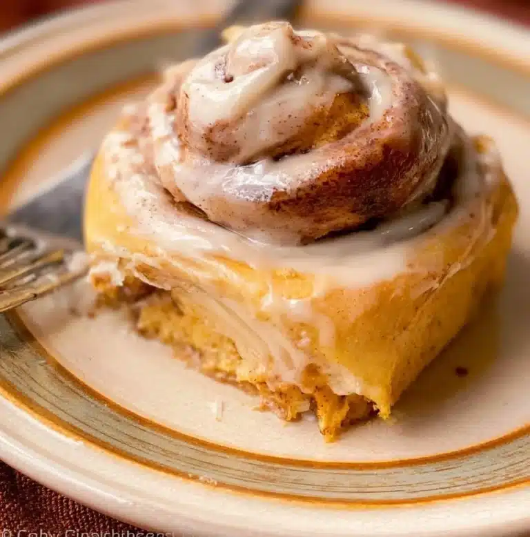 Freshly baked pumpkin cinnamon rolls drizzled with cream cheese icing
