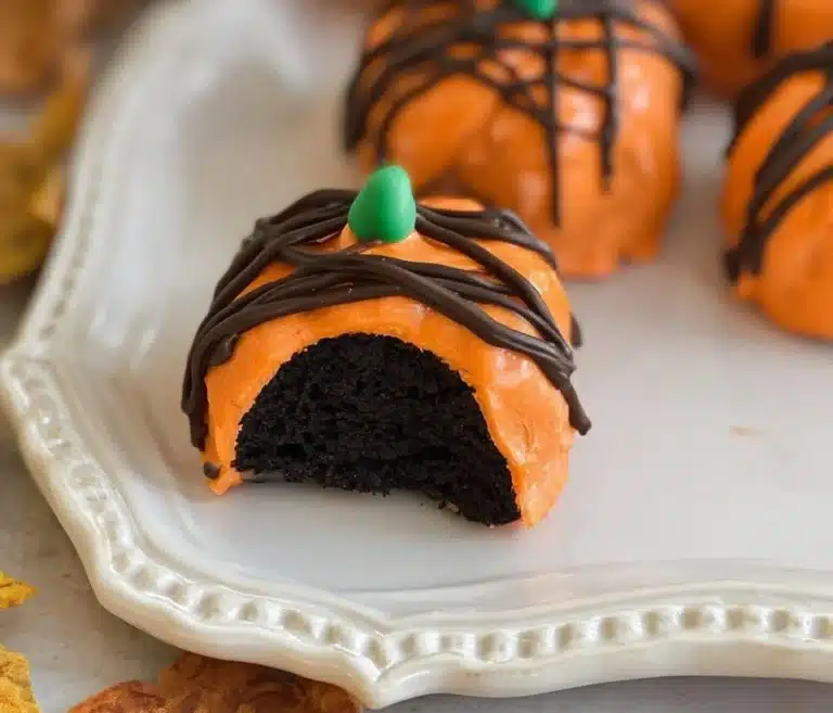 Plate of homemade Pumpkin Oreo Balls decorated with chocolate drizzle.