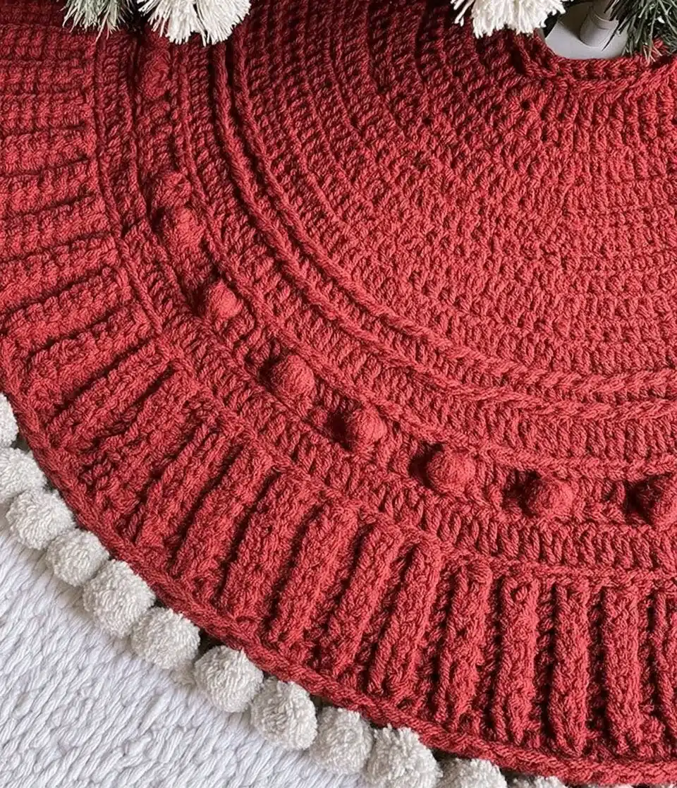 A decorative tree skirt placed under a beautifully adorned Christmas tree.